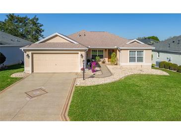 Charming single-story home featuring a two-car garage, decorative driveway, and nicely landscaped front yard at 17660 Se 81St Timberwood Ter, The Villages, FL 32162