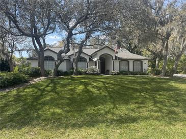 Charming single-story home featuring a well-manicured lawn and mature trees in a quiet neighborhood setting at 33021 Indian Woods Dr, Leesburg, FL 34788