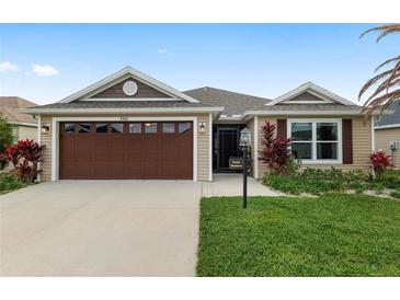 Charming single-story home featuring a well-manicured lawn and attached two-car garage at 5510 Thome Loop, The Villages, FL 32163