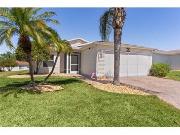 Charming single-story home features lush landscaping, palm trees, and a brick-paved driveway at 841 Eagles Lndg, Leesburg, FL 34748