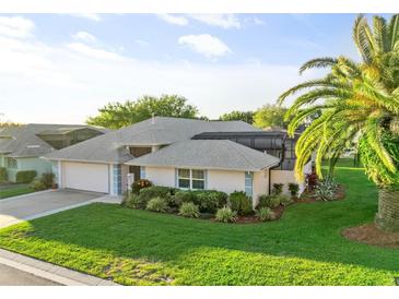 Beautiful single-story home featuring a well-maintained lawn, mature landscaping, and a screened in lanai at 5953 Sailboat Ave, Tavares, FL 32778