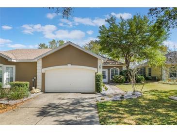 Charming single-story home with a two-car garage, a well-maintained lawn, and beautiful landscaping at 6200 Topsail Rd, Lady Lake, FL 32159