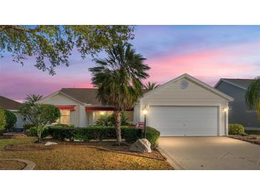 Charming single-story home features a well-manicured lawn, palm tree, and a two-car garage at 891 Lucky Ln, The Villages, FL 32162