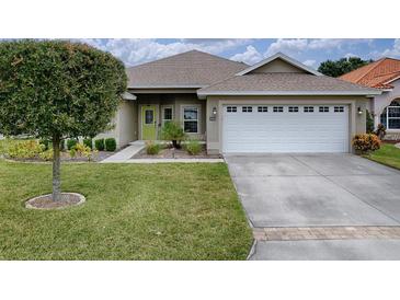 Charming single-story home featuring a well-manicured lawn, a green door, and an attached two-car garage at 30454 Island Club Dr, Deer Island, FL 32778