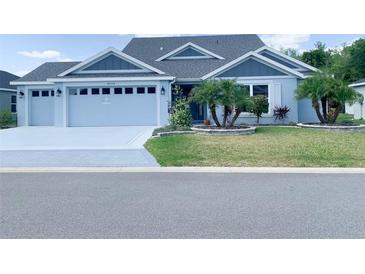 Charming single-story home with blue exterior, manicured lawn, and well-maintained landscaping at 6444 Mcknight Loop, The Villages, FL 34762