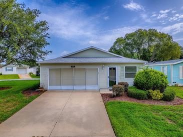 Charming single-story home featuring a well-manicured lawn and a convenient attached garage at 701 Cottage Park Ln, Leesburg, FL 34748