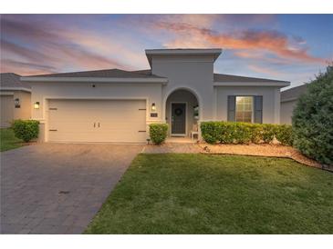 Charming home featuring a paver driveway, attached garage, and well-maintained landscaping at 916 Carmillion Ct, Groveland, FL 34736