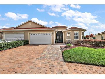 Beautiful single-story home with brick driveway, well-manicured landscaping, and a two-car garage at 10199 Mainsail Dr, Oxford, FL 34484