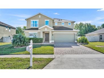 Charming two-story home with a well-manicured lawn and a brick paved driveway at 10219 Lenox St, Clermont, FL 34711