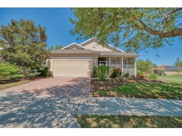 Inviting single-story home with a well-manicured lawn, mature trees and a charming front porch at 117 Falling Acorn Ave, Groveland, FL 34736