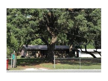 Charming single-story home with mature trees and fenced yard, offering a serene and private setting at 136 S Commercial St, Coleman, FL 33521