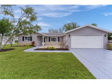 Charming single-story home with well-manicured lawn, gray siding, and a two-car garage at 17965 Se 107Th Ct, Summerfield, FL 34491