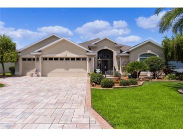 Charming single-story home with a three-car garage, landscaped front yard, and brick paver driveway at 1965 Evans Prairie Trl, The Villages, FL 32163