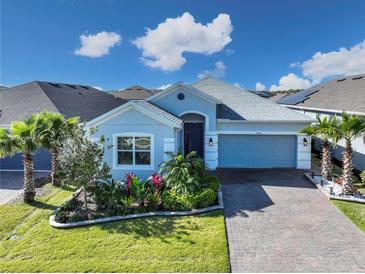 Charming single-story home with a brick driveway, manicured lawn and tropical landscaping at 2183 Ridge Pointe Ln, Clermont, FL 34715