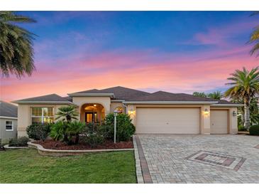 Charming single-story home with a three-car garage, lush landscaping, and a brick-paved driveway at 2428 Maverick Way, The Villages, FL 32162