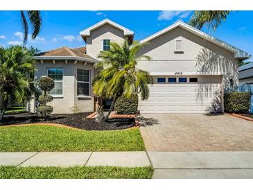 Charming two-story home boasts a two-car garage, manicured lawn, and mature tropical landscaping at 4419 Azure Isle Way, Kissimmee, FL 34744