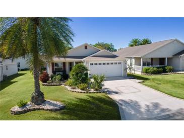 Charming single-story home with a well-manicured lawn, a palm tree, and a two-car garage at 2186 Quinn Ln, The Villages, FL 32162