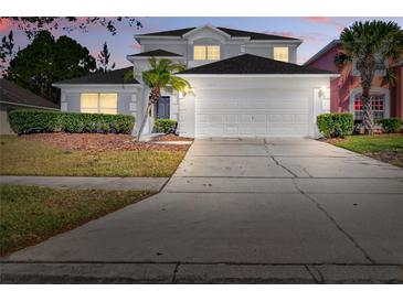 Charming two-story home with a two-car garage and well-maintained landscaping with small palm tree at 4703 Golden Beach Ct, Kissimmee, FL 34746