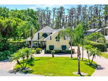 Stunning two-story home featuring a brick circular driveway, lush landscaping, and mature trees at 10417 Lake Louisa Rd, Clermont, FL 34711