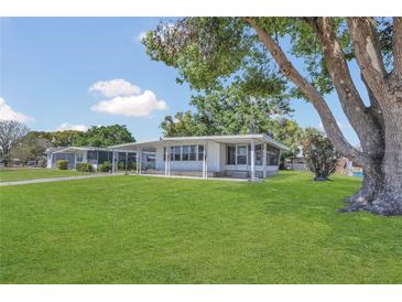 Charming single-story home with a well-maintained lawn and a large tree providing shade at 1112 Elkhart Cir, Tavares, FL 32778