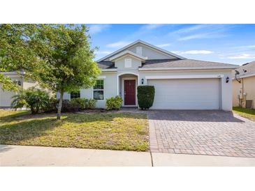Charming single-story home with a well-manicured lawn and a brick-paved driveway at 118 Green Branch Blvd, Groveland, FL 34736