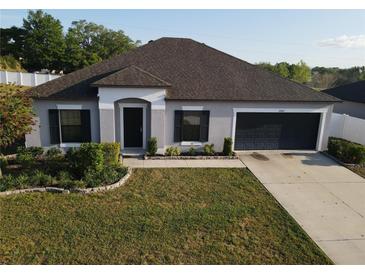 Charming single-story home featuring a well-manicured lawn, a two-car garage, and classic dark shutters at 12807 Sugar Ct, Grand Island, FL 32735