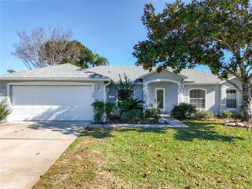 Charming single-story home with a well-maintained lawn and mature trees on a sunny day at 1407 Island Cove Dr, Deland, FL 32724