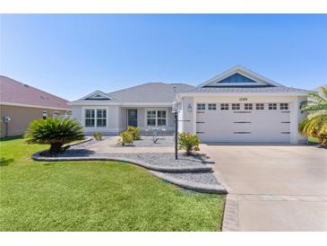 Charming home featuring a well-manicured lawn, beautiful landscaping, and an attached two car garage at 1589 Armstrong Ave, The Villages, FL 32163