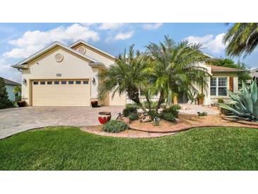Charming home featuring manicured landscaping, a brick driveway, a two-car garage, and elegant palm trees at 17066 Se 111Th Ter, Summerfield, FL 34491