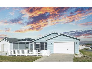 Charming home with a white picket fence and manicured lawn under a captivating sunset sky at 1723 Morelos Rd, The Villages, FL 32159