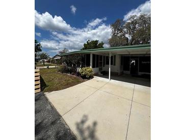 Well-maintained exterior with a driveway, lush lawn, and mature landscaping at 201 Jacaranda Dr, Leesburg, FL 34748
