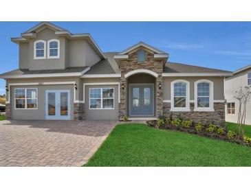Charming two-story home features stone accents, arched entry, and well-manicured lawn at 2176 Keystone Pass Blvd, Minneola, FL 34715