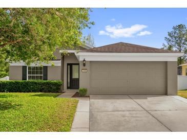 Charming single-story home with a well-manicured lawn, a two car garage, and lush green shrubbery at 2988 Santa Maria Ave, Clermont, FL 34715