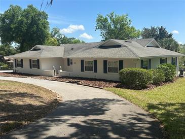 Charming single-story home with a long, curved driveway, manicured landscaping, and traditional architecture at 5331 Magnolia Ridge Rd, Fruitland Park, FL 34731