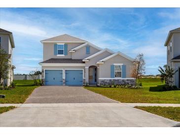Charming two-story home featuring a two-car garage and nicely landscaped front yard with blue shutters at 5457 Marshelder St, Apopka, FL 32712