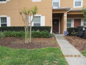 Charming townhome featuring manicured landscaping, healthy trees, and a welcoming entrance at 1010 Chelsea Dr, Davenport, FL 33897