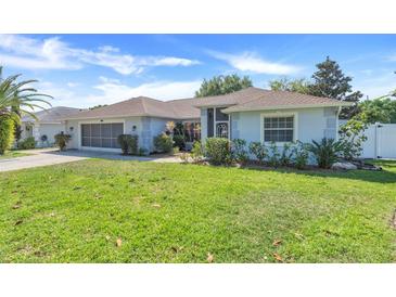 Charming single-story home with a well-manicured lawn, beautiful landscaping, and an attached two-car garage at 10257 Dovehill Ln, Clermont, FL 34711