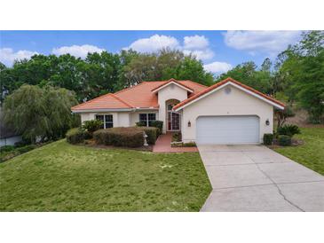 Charming single-story home with a Spanish tile roof, lush lawn, and mature landscaping at 11497 Sw 82Nd Court Rd, Ocala, FL 34481