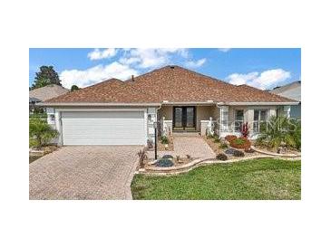 Charming home with a brick driveway, well-manicured lawn, and a welcoming front entrance at 1210 Weaton Ct, The Villages, FL 32162