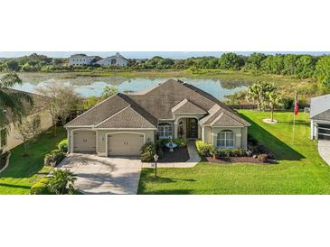 An attractive home features a three-car garage, mature landscaping, and is situated on a picturesque lot with water views at 1723 Carrera Dr, The Villages, FL 32159