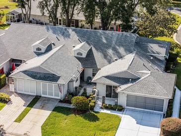 Charming home featuring well-manicured landscaping, a two-car garage, and a classic, inviting facade at 26032 Newcombe Cir, Leesburg, FL 34748