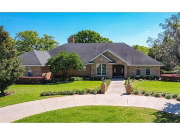 Charming brick home with manicured lawn, mature trees, and long driveway entrance at 2756 Sequoyah Dr, Haines City, FL 33844