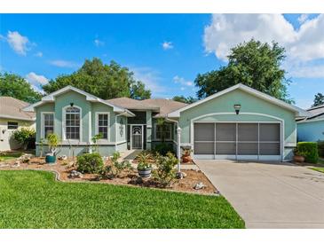 Charming one-story home with beautiful landscaping, lush lawn, and a screened two-car garage on a sunny day at 4717 Inverness Dr, Leesburg, FL 34748