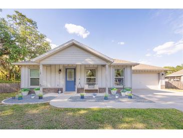 Charming single-Gathering home featuring a blue front door, an attached garage, and nicely landscaped front yard at 548 E Belt Ave, Bushnell, FL 33513