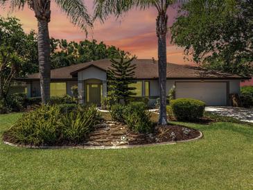 Charming one-story home with well-manicured lawn and lush landscaping featuring palm trees and decorative rock garden at 5906 Prince Philip Ct, Leesburg, FL 34748