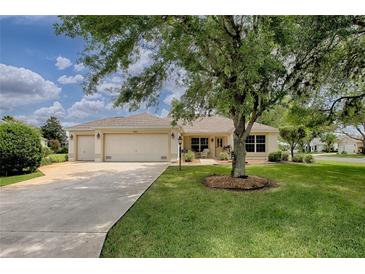 Charming single-story home with a three-car garage, manicured lawn, and mature landscaping at 725 Beldon Ct, The Villages, FL 32162