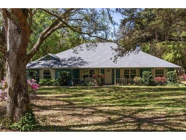 Charming single story home featuring a well-maintained lawn, mature trees, and welcoming front porch at 10159 Se 174Th St, Summerfield, FL 34491