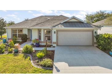 Charming single-story home with a well-manicured lawn and a two-car garage with a retractable screen at 1061 Woodruff St, The Villages, FL 32162