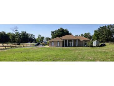 A single-story home boasts a sprawling lawn, complemented by mature trees, and a columned entryway at 13013 County Road 561A, Clermont, FL 34715