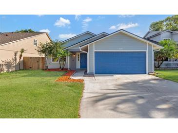 Charming single-story home featuring a blue garage door and well-maintained front lawn at 1566 Lawndale Cir, Winter Park, FL 32792